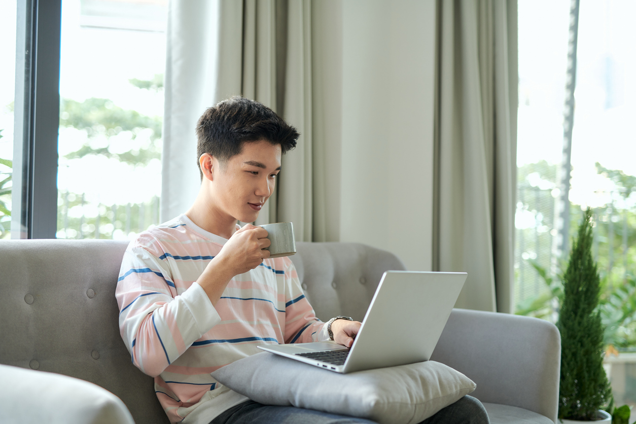 Image of man drinking coffee browsing on a laptop
